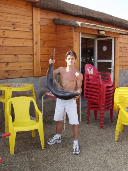 Miembro del equipo de El Parque sosteniendo una gran pieza de pescado fresco junto al restaurante